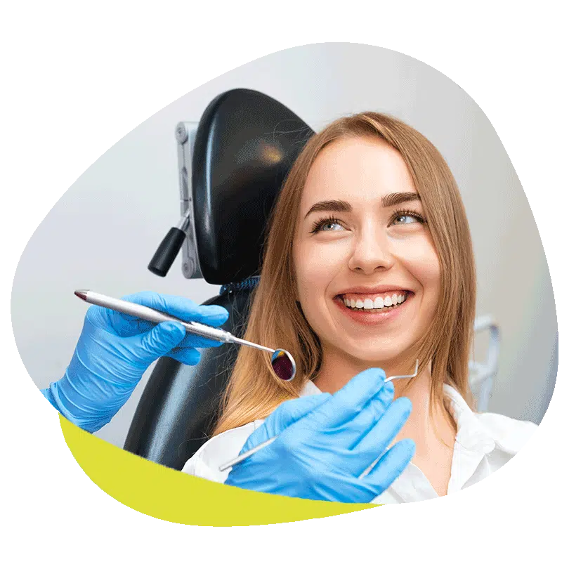 Frau sitzt lächelnd auf einem Zahnarztstuhl